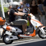 Modern eschopper electric scooter with chopper design parked on city street showing battery pack and handlebars
