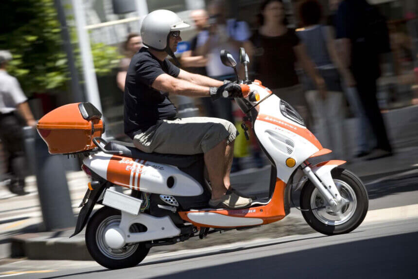 Modern eschopper electric scooter with chopper design parked on city street showing battery pack and handlebars