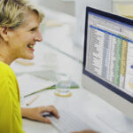 Accountant using payroll software dashboard to manage multiple clients with automated features and compliance tools