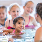 Water safety instructor teaching swimming lessons to children in pool during Red Cross certification training