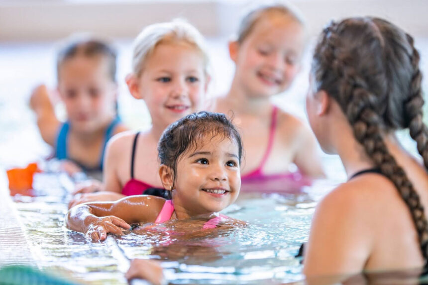 Water safety instructor teaching swimming lessons to children in pool during Red Cross certification training