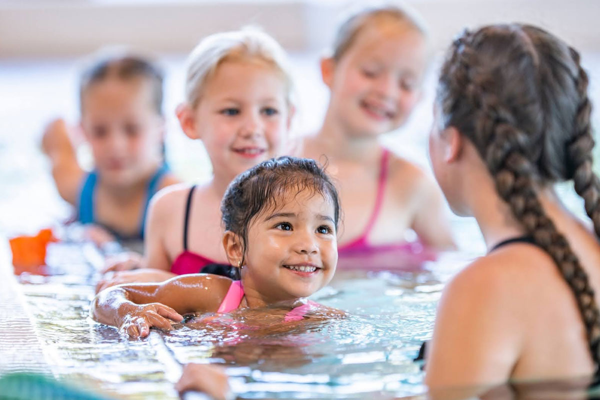 Water safety instructor teaching swimming lessons to children in pool during Red Cross certification training