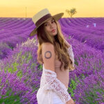 Charmane Star in lavender field wearing white dress and hat representing her net worth journey