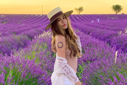 Charmane Star in lavender field wearing white dress and hat representing her net worth journey