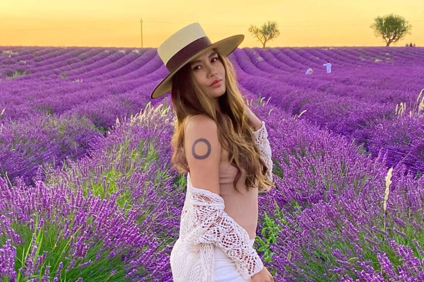Charmane Star in lavender field wearing white dress and hat representing her net worth journey