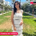 Linda Furrha net worth in white tiered ruffle dress standing in a landscaped courtyard, Linda Furrha net worth article image