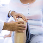 Doctor examining patient's knee for septic arthritis symptoms during medical consultation
