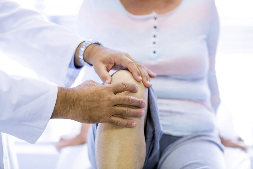Doctor examining patient's knee for septic arthritis symptoms during medical consultation