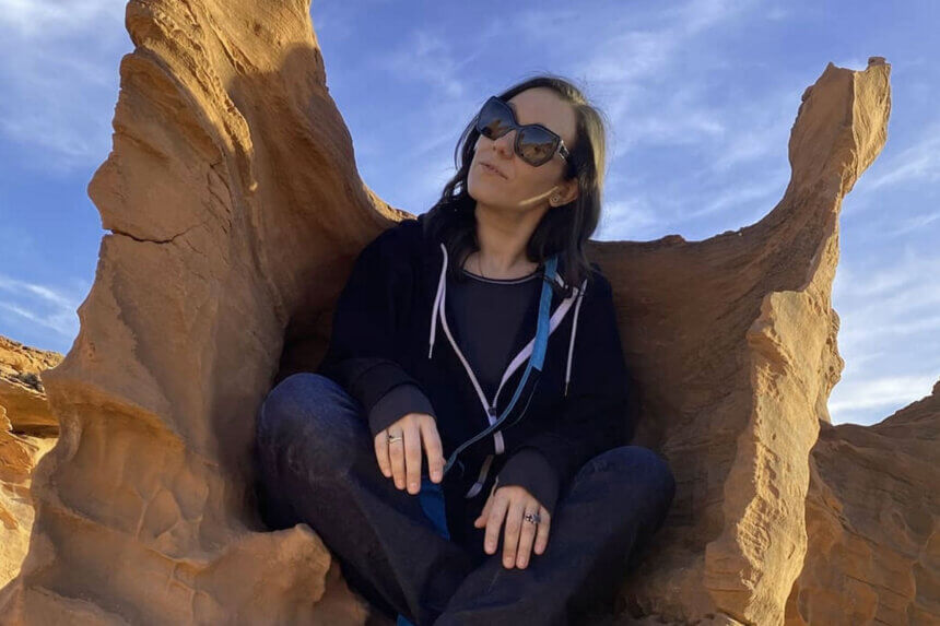 Woman sitting in desert rock formation representing Sinn Sage net worth success story