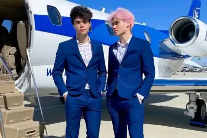 Stokes Twins Net Worth shown through Alan and Alex Stokes in blue suits standing in front of private jet