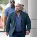 Alex Jones walking outside courthouse discussing net worth and bankruptcy proceedings in 2025