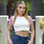Anna Claire Clouds wearing white crop top and jeans showing her net worth success in 2025
