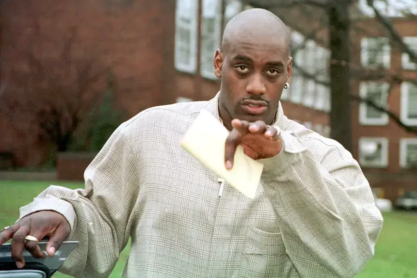 Anthony Mason pointing while wearing a plaid jacket during his NBA career representing his net worth and basketball legacy