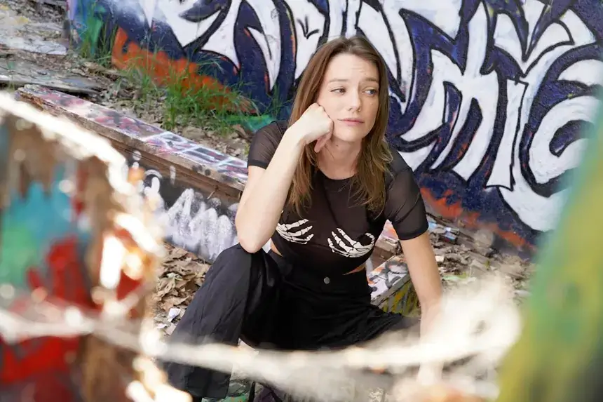 Kenna James sitting casually in front of graffiti wall discussing her net worth and career earnings