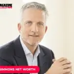 Bill Simmons in navy suit, gray hair and beard, hands clasped