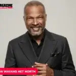 Damon Wayans smiling in a dark double-breasted suit against a gray backdrop