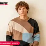 young man with curly hair in colorblock sweater against beige wall
