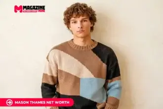 young man with curly hair in colorblock sweater against beige wall