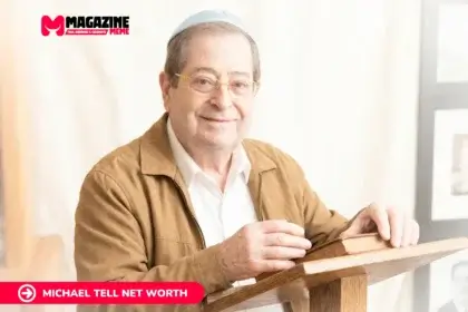 older man in glasses and blue kippah reading at a wooden lectern