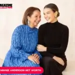 Two women share a laugh while seated together, one in a blue dress, one in black