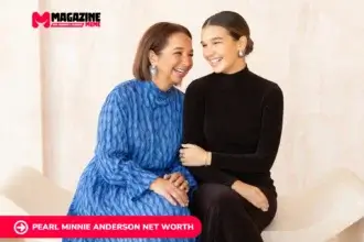 Two women share a laugh while seated together, one in a blue dress, one in black