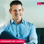 Adam Kinzinger smiling in a blue shirt on a couch, featured for his net worth article