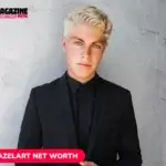 Ben Azelart in black suit and shirt, platinum-blond hair, for net worth article